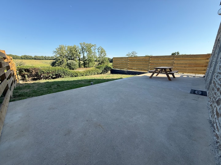 Terrasse extérieure du gîte Austral avec table pique-nique et vue panoramique sur les prairies bretonnes