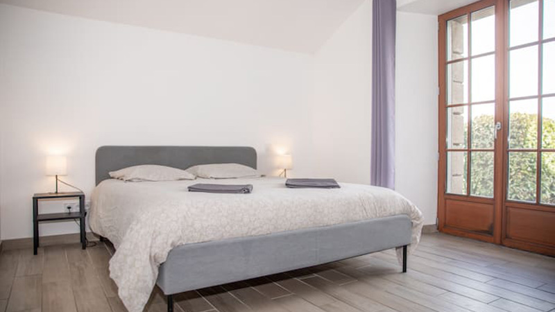 Chambre double avec lit 160 cm et porte-fenêtre à petits carreaux dans le gîte Mistral près de Saint-Malo