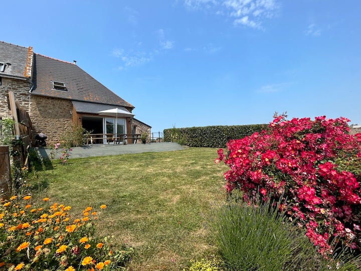 Jardin fleuri et terrasse couverte du gîte Mistral, avec roses et vue sur la campagne près de Saint-Malo